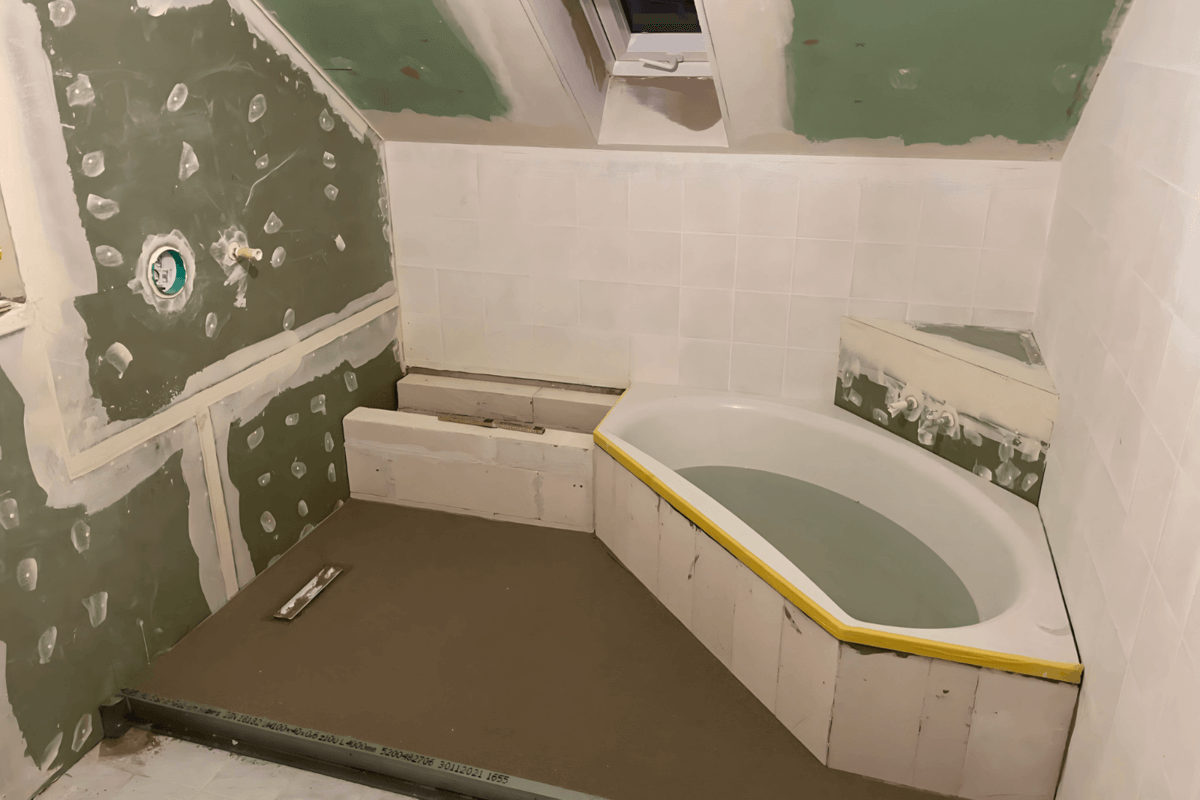 Badezimmer in der Renovierungsphase mit vorbereiteten Wänden und Eckbadewanne.